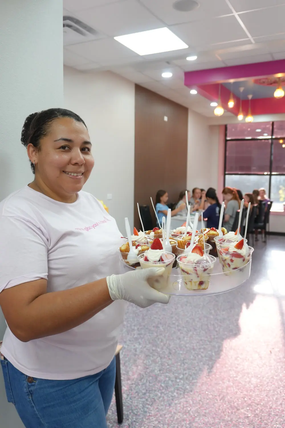 A person holding a tray of desserts beside the party tables.