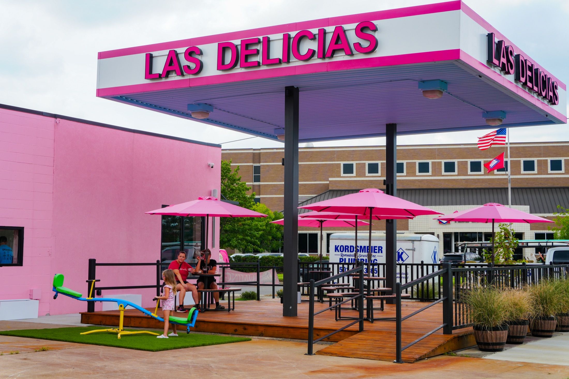 The Harkrider Street shop under its pink canopy, with picnic tables, umbrellas and a seesaw on the deck