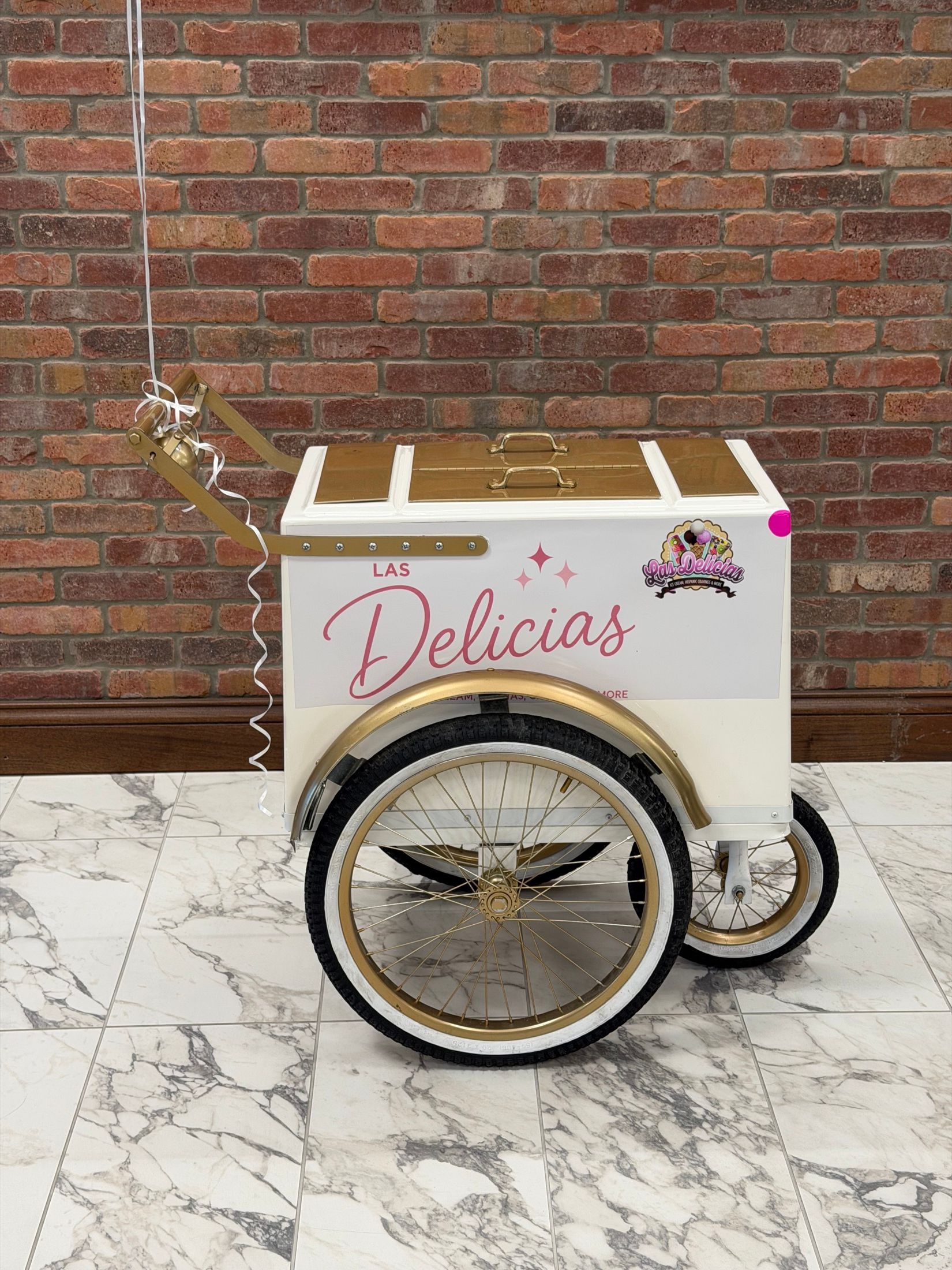 Close view of the Las Delicias push cart showing its gold trim, spoked wheels and painted name